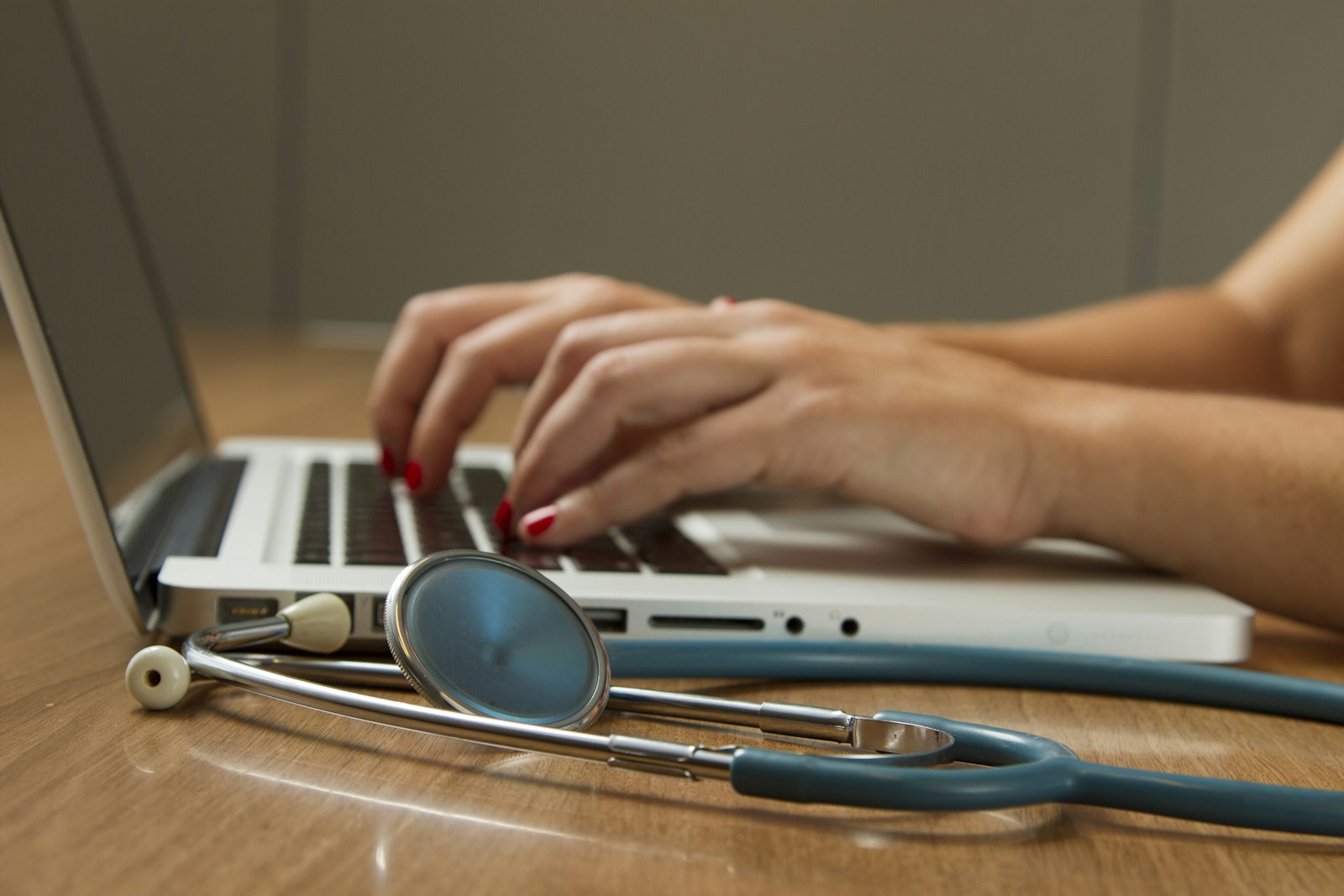 Hands typing on a laptop beside a stethoscope while preparing a medical chronology