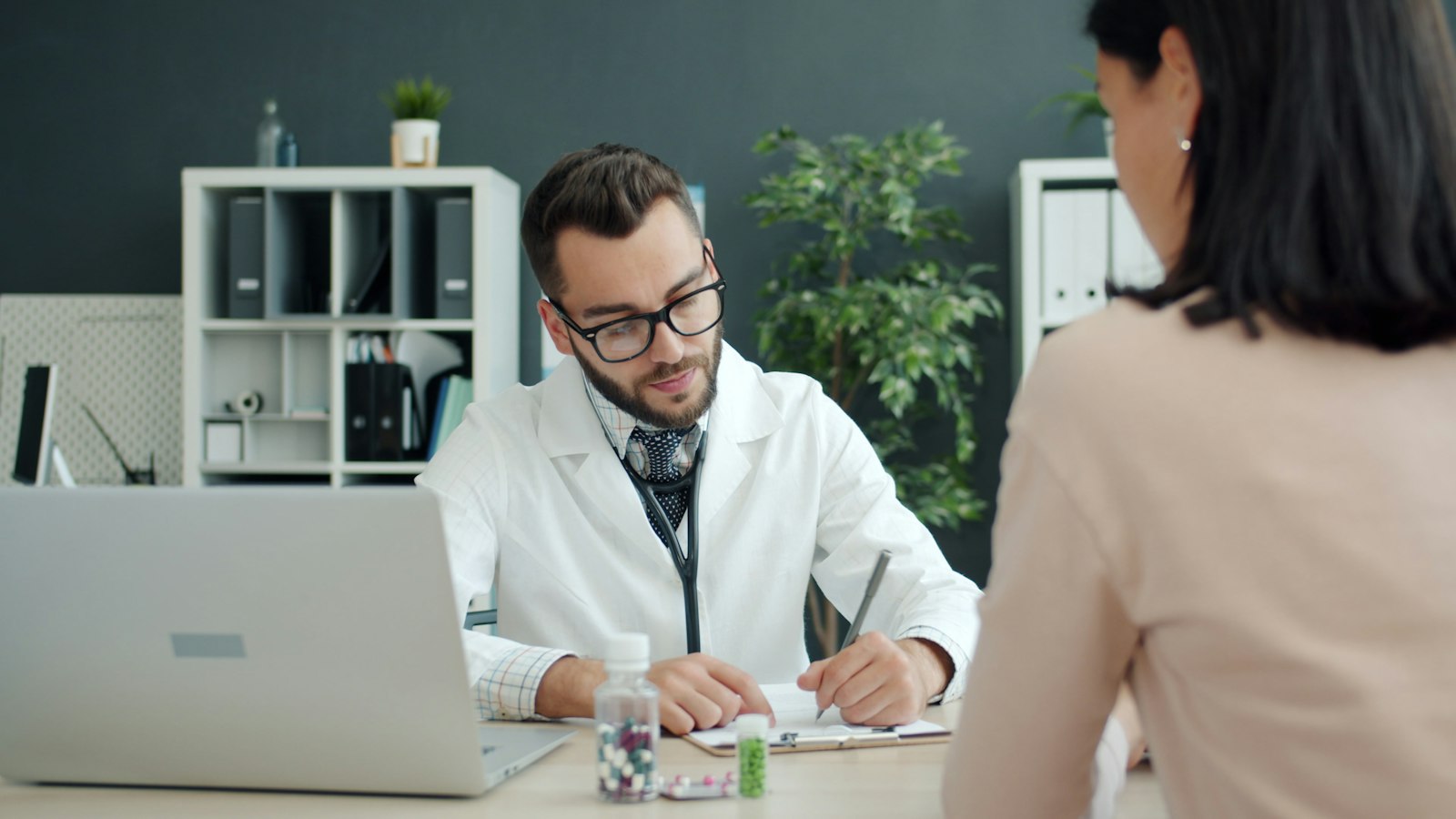 Clinician taking notes during a medical examination with a patient