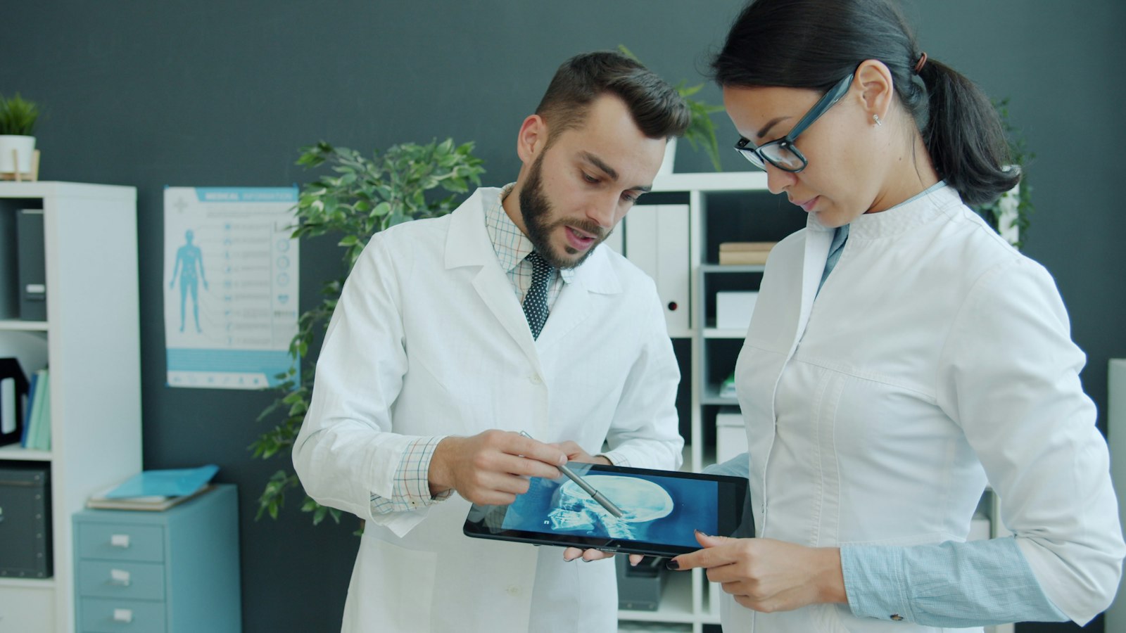 Two physicians reviewing a medical scan on a tablet