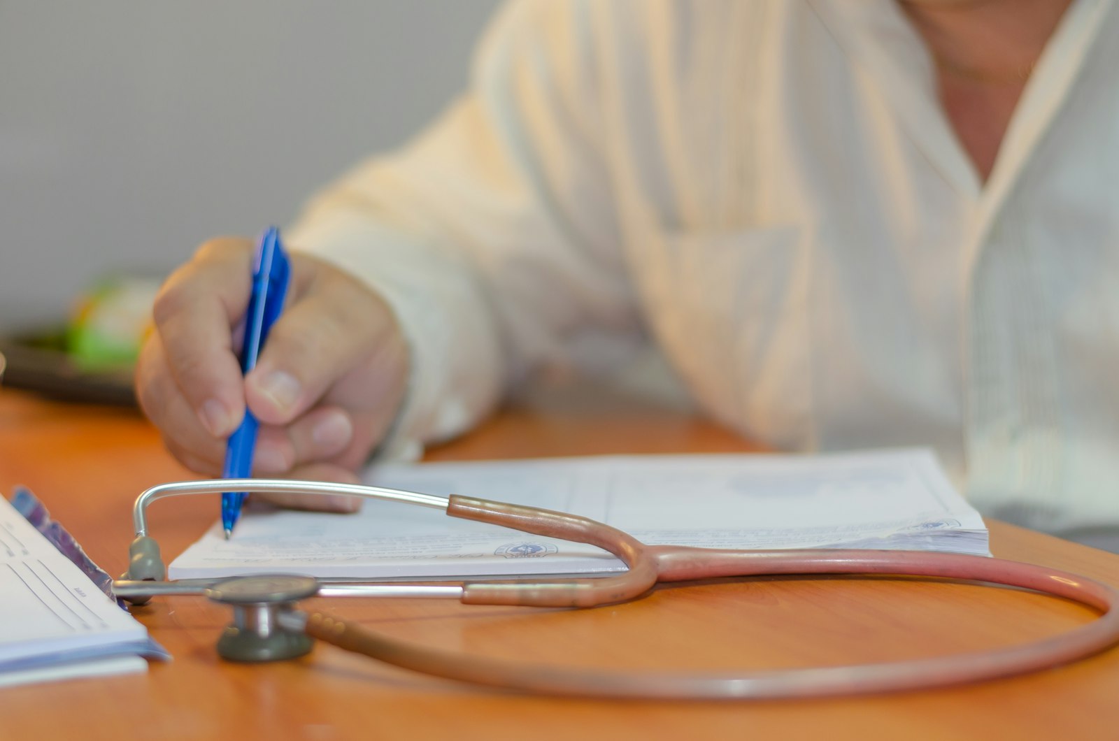 Hand annotating a medical record next to a stethoscope